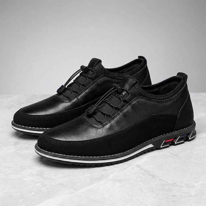 Sutri Leather Slip-On Shoes — Black, pair in three-quarter view on light-grey marble