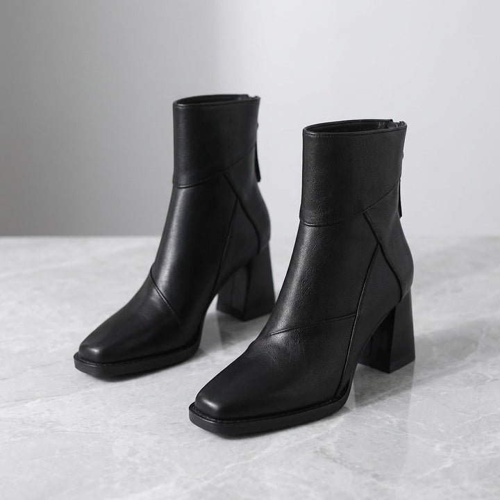 Tropea Paneled Ankle Boots — Black, pair of boots, three-quarter view on light grey marble