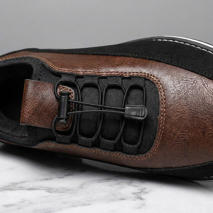 Sutri Leather Slip-On Shoes — Chestnut Brown, close-up of the elastic no-tie laces and stitched upper on light-grey marble
