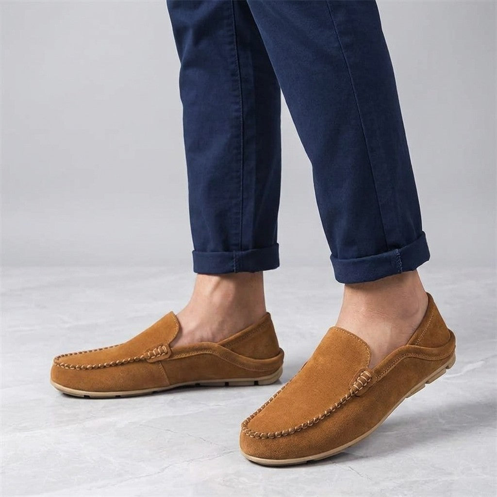 Menaggio Suede Loafers — Apricot, worn sockless with cuffed navy chinos, knee-down on light grey marble