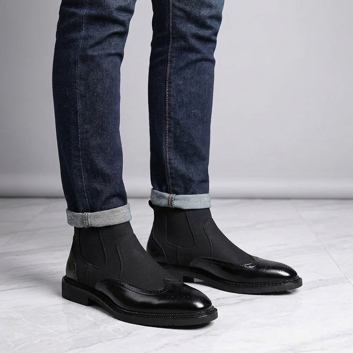 Montefalco Brogue Chelsea Boots — Black, worn with cuffed dark jeans, knee-down on light grey marble
