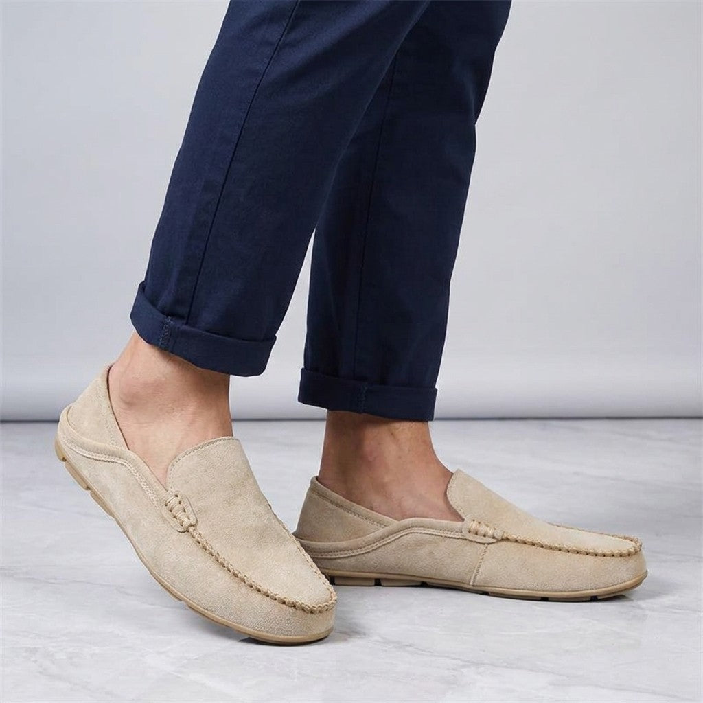 Menaggio Suede Loafers — Khaki, worn sockless with cuffed navy chinos, knee-down on light grey marble