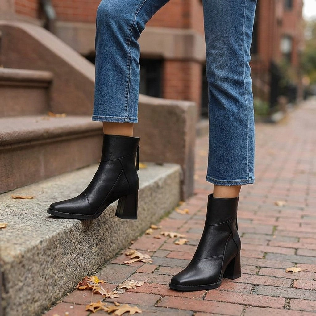 Tropea Paneled Ankle Boots — Black, worn with cropped blue jeans on a brick sidewalk by brownstone steps