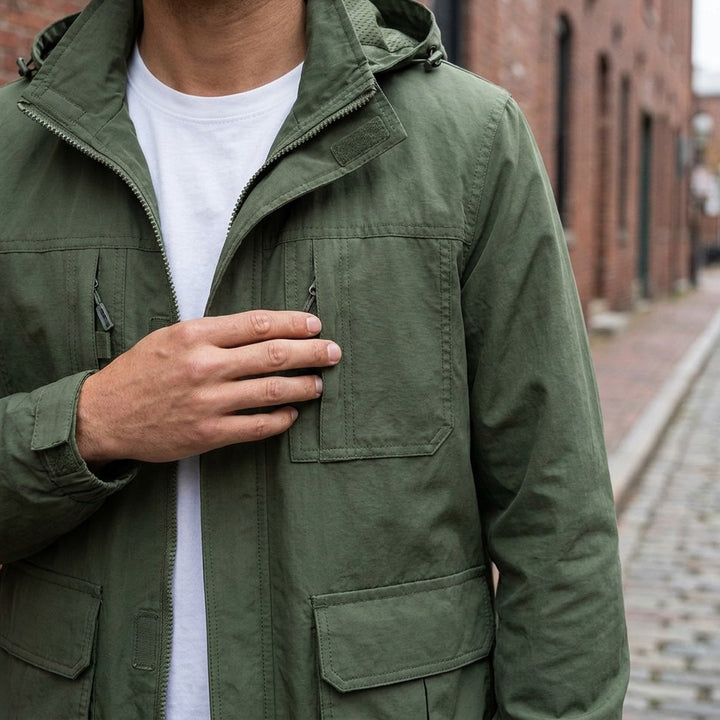 Close-up of the Pavia Hooded Cargo Jacket in Army Green worn over a white tee, showing the stand collar, hood and velcro chest pockets