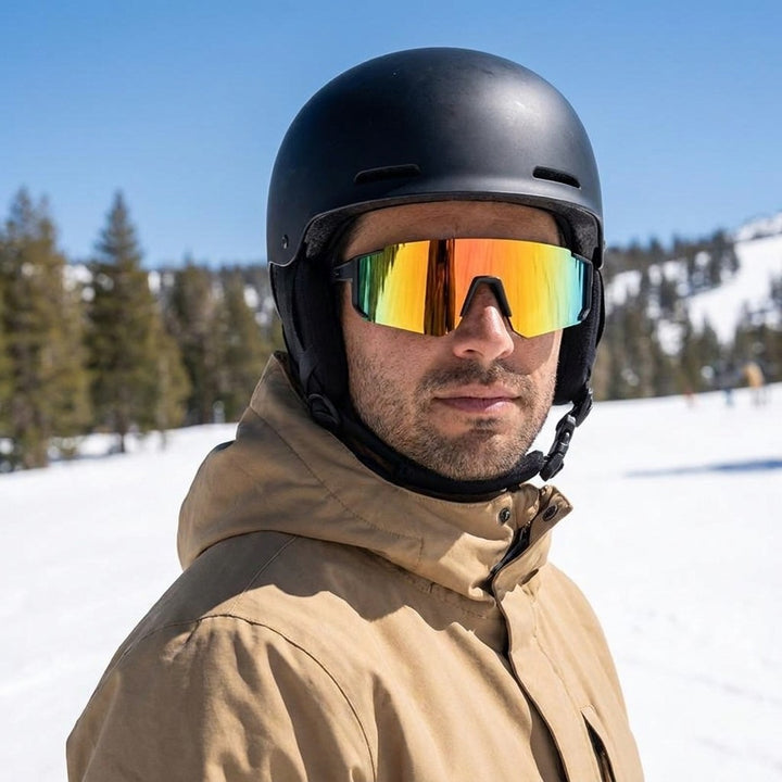 Scilla Shield Sunglasses — Black / Fire Mirror, worn by a man in a helmet snowboarding sunny spring snow at Mammoth