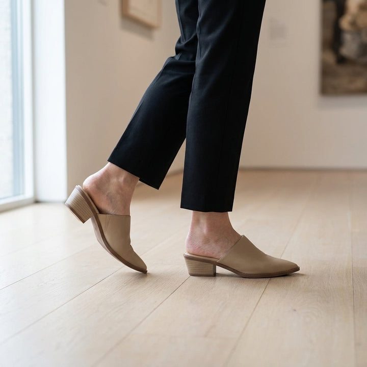 Sabina Leather Mules — Sand, worn mid-stride in a gallery interior