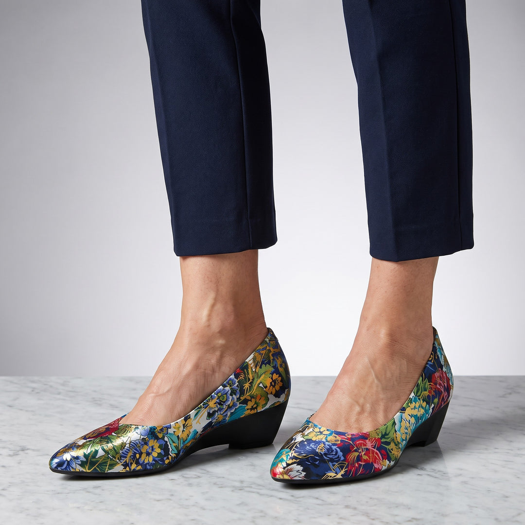 Camogli Floral Pumps — Teal Floral, worn by a woman in navy cropped trousers, knee down, on marble