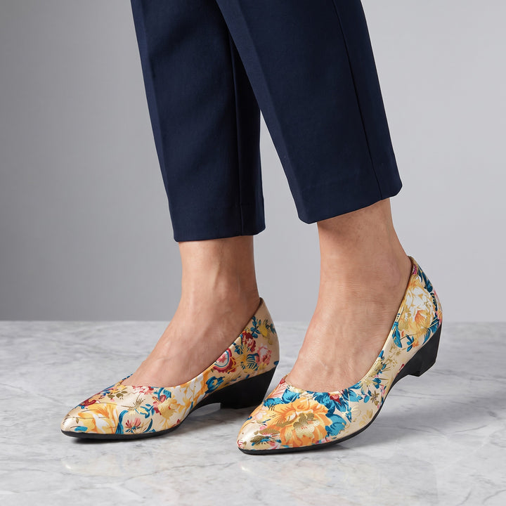 Camogli Floral Pumps — Cream Floral, worn by a woman in navy cropped trousers, knee down, on marble